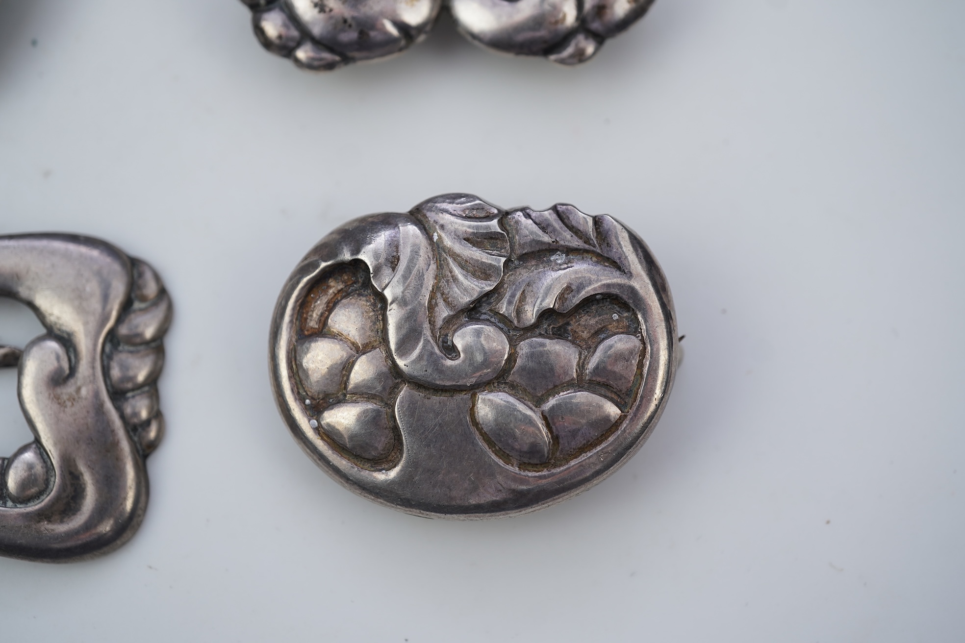 An Arts & Crafts silver slide and three silver brooches, probably Denmark, first half 20th century